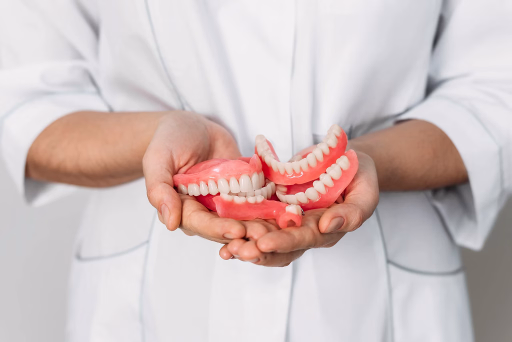 Orthopedic dentist holding multiple sets of custom dentures, showcasing durable and natural-looking dental restorations at Rosemary Dental Spa in Albuquerque, New Mexico.