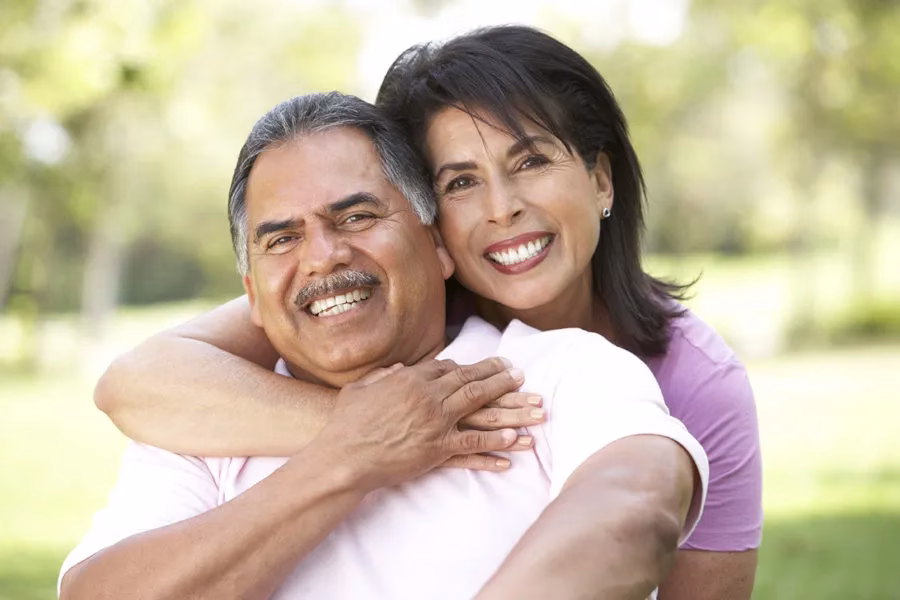 Smiling couple embracing outdoors, showcasing confidence and happiness, representing the positive impact of custom dentures on quality of life at Rosemary Dental Spa in Albuquerque.